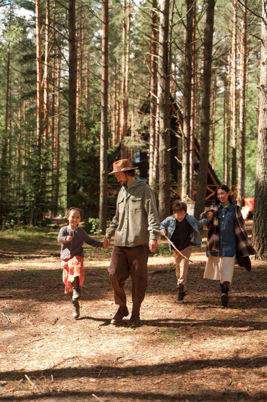 Parents and two children walking together through a sunlit forest